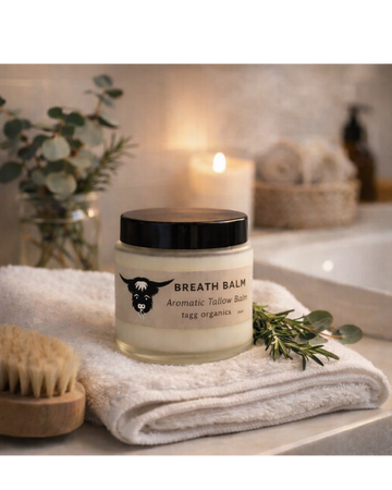Jar of breath balm on a towel with a candle and plant in the background
