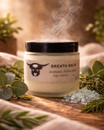 Jar of Breath Balm with steam rising, surrounded by greenery on a wooden surface.
