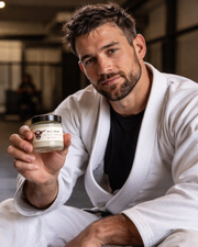 Man in a white robe holding a jar of cream in an indoor setting