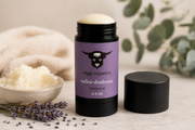Tagg Organics Talloe Deodorant stick in a lavender purple container with a black cap removed and placed beside it, styled with lavender sprigs, a bowl of cream deodorant, and soft neutral props on a light surface.