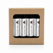 A set of four Tark Organics hair oil bottles displayed in a clear window of a brown kraft paper box, on a white background.