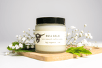 Bull Balm jar on a wooden board with white flowers and green leaves on a light gray background