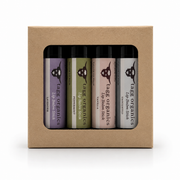 A set of four lip balm sticks in a kraft paper gift box. The lip balms are from the brand Tags Organics and include lavender, peppermint, vanilla, and unscented variants with different colored labels.